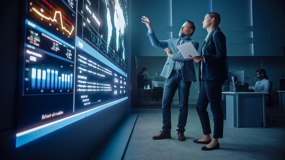 Man and woman professionals looking at a big screen using AI at Triad Executive Advisors